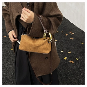 Close-up of golden metal ring handle and brown suede texture on a Boston handbag