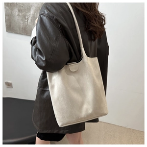 Detailed side view of beige minimalist suede tote bag carried by a model