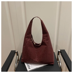 Close-up of vintage dark red leopard print embossed tote bag on a stylish leather chair