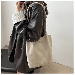 Detail view of beige matte suede bucket tote bag worn on shoulder by a model