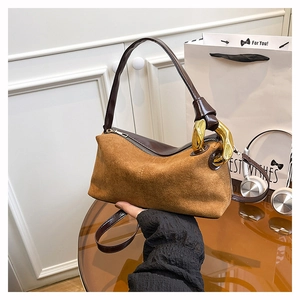 Detail view of brown suede handbag with chunky gold chain decoration and smooth leather handles