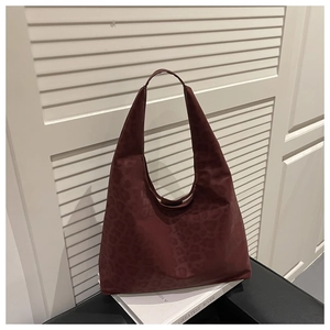 Detail view of burgundy leopard print hobo tote bag on a black leather chair