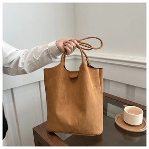 Detail of dark brown suede tote bag featuring cylindrical handles and a slim shoulder strap