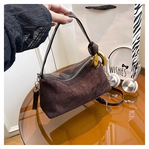 Detail of dark brown suede and leather handbag with bold gold ring and knot accent