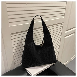 Detail of black leopard print hobo bag in soft suede material placed on a white book
