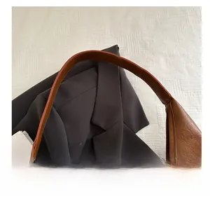 Détail de la poignée large et confortable d'un sac porté épaule en cuir marron souple