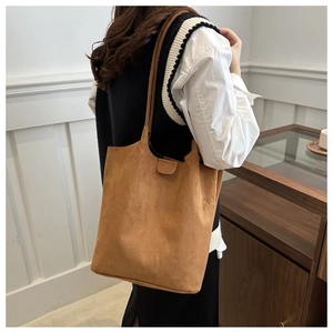 Detail view of brown suede bucket bag with vintage buckle on minimalist shoulder strap