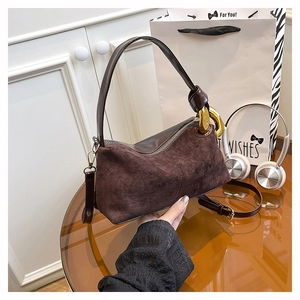 Detail of dark brown semi-moon bag with suede texture and gold chain link buckle