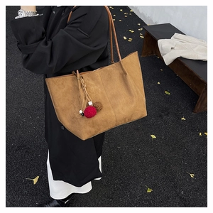 Macro shot of large dark brown frosted tote bag with a decorative fur ball charm