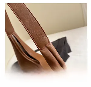 Gros plan sur la texture du cuir marron et les détails de couture d'un grand sac porté épaule