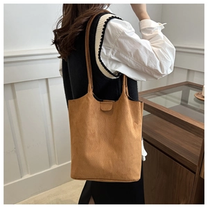 Detail view of the brown suede bucket bag texture and reinforced shoulder strap stitching