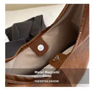 Gros plan du fermoir magnétique sur un sac hobo en cuir marron avec doublure en tissu
