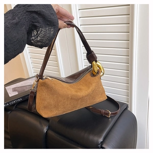 Detail view of suede and leather vintage handbag with golden chain buckle and zip closure