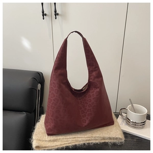 Detailed macro view of burgundy leopard-print embossed texture on suede tote bag