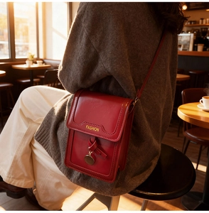 Détail d'un petit sac à bandoulière rouge en cuir avec imprimé mode et pendentif en nœud