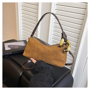 Close-up of caramel suede Boston bag featuring dark brown handles and chunky gold chains