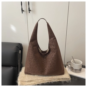 Detail of dark brown tote bag with subtle leopard pattern on soft suede fabric