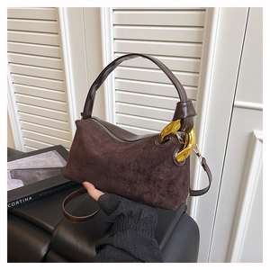 Detail of dark brown suede Boston bag featuring a bold gold chain link and dual strap design