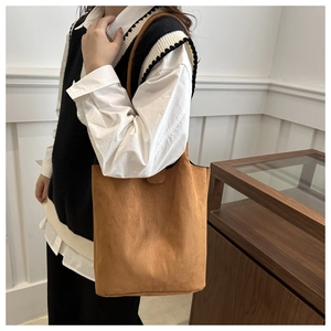 Detail of soft brown suede bucket bag texture and minimalist shoulder strap design
