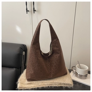 Detailed close-up of dark brown leopard print tote bag on soft knit background