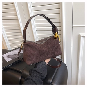 Close-up of a retro brown suede handbag with luxury gold hardware and zipper detail