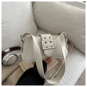 Détail du sac crème en cuir avec boucle décorative et œillets argentés élégants