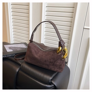 Detail view of dark brown suede handbag with oversized gold chain hardware accent