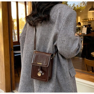 Détail d'un mini sac bandoulière vintage marron foncé avec pendentif doré élégant