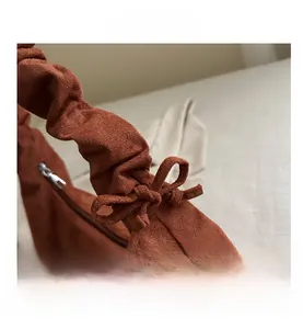 Détail de sac à main en daim marron avec plis élégants et décoration de nœud papillon