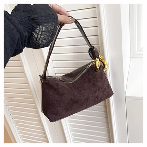 Detail of dark brown suede handbag with large gold metal ring and smooth leather handle