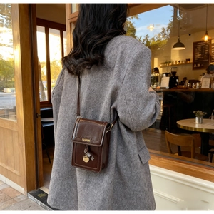 Détail du sac bandoulière vintage en cuir huilé marron avec lettrage FASHION doré