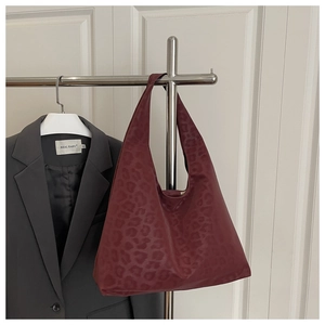 Detail of burgundy leopard embossed hobo tote bag hanging on a professional metal rack