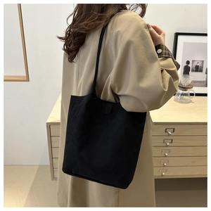 Minimalist black matte bucket bag worn by a model in a stylish indoor setting