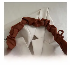 Vue détaillée de l'anse plissée et de la texture en daim d'un sac à bandoulière marron