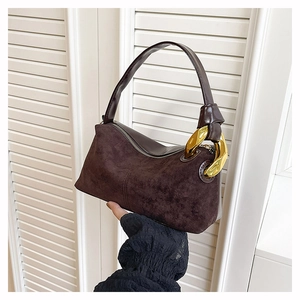 Detail of dark brown suede handbag featuring a unique gold twisted metal handle ring