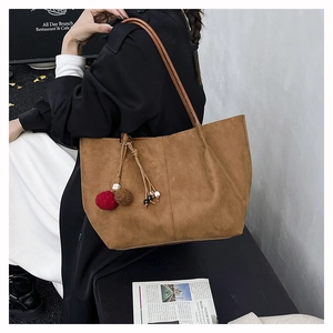 Detail of warm brown frosted suede tote bag with decorative tassel and leather handles