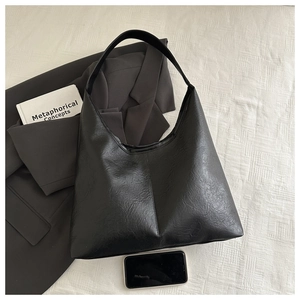 Détails du grand sac cabas noir en cuir texturé montrant des courbes douces et sa capacité