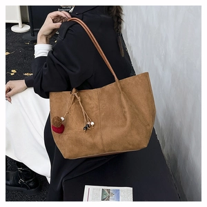 Dettaglio borsa tote in pelle scamosciata marrone con cuciture verticali e nappina