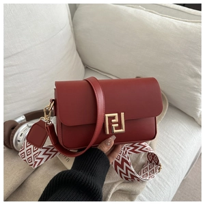 Detail of red crossbody bag with golden geometric buckle and patterned woven strap