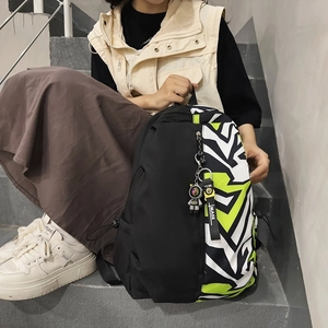 Fashionable black backpack with neon green graffiti prints and astronaut keychain