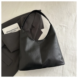 Gros plan d'un sac hobo noir minimaliste avec texture cuir vintage et large bandoulière