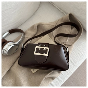 Détail d'un sac à main en cuir marron foncé avec boucle argentée et bandoulière à œillets