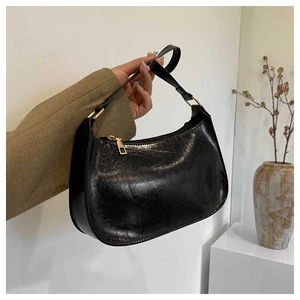 Detail of glossy black pleated underarm bag with gold zipper and minimalist vintage texture