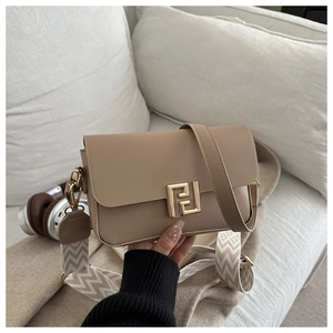 Detail of beige crossbody bag with gold F logo and decorative woven strap on white sofa