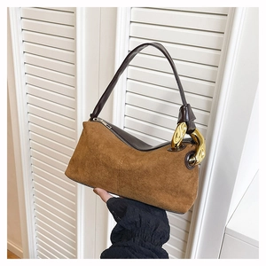 Detail of brown suede tote bag with stylish oversized gold chain links on the shoulder strap