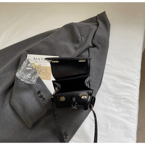 Détail de l'intérieur d'un petit sac carré noir avec boucle magnétique dorée et compartiments