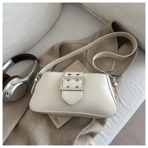 Détail du sac sous le bras crème avec sangle décorative et boucle en métal argenté