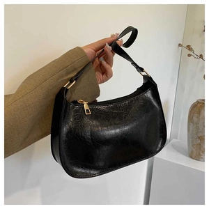 Detail view of a vintage black glossy leather underarm bag with gold hardware accessories