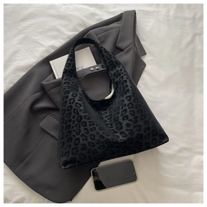 Detailed view of black leopard print tote bag with soft velvet texture on a bedsheet