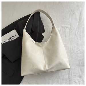Vue détaillée du sac cabas crème texturé sur tissu blanc et décor épuré